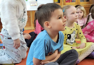 Dzieci siedzą na dywanie w bibliotece