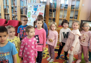 Dzieci stoją na tle regałów w bibliotece