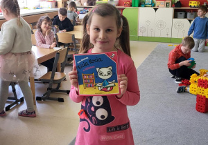 Dziewczynka prezentuje książkę wypożyczoną z biblioteki