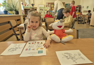 Dzieci przy stolikach wykonują zadania na karcie pracy