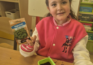 Dziewczynka pokazuje nasiona majeranku.