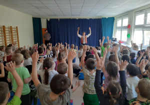 Dzieci stoją na widowni z uniesionymi rękoma