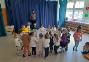 Dzieci stoją w kole, trzymając w rękach chustę