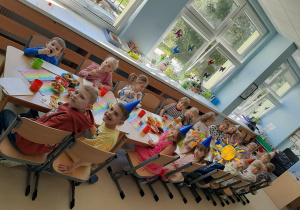 Dzieci siedzą przy stole z poczęstunkiem i pozują do zdjęcia