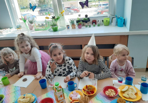 Dziewczynki siedzą przy stole i jedzą przekąski