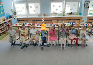 Jubilaci siedzą na krzesłach, w rękach trzymają prezenty