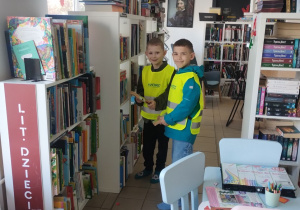 Dwaj chłopcy wybierają książki do wypożyczenia
