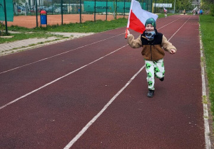 Chłopiec biegnie z flagą Polski