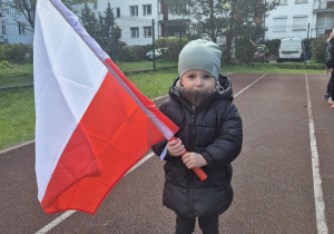 Chłopiec pozuje do zdjęcia z flagą Polski