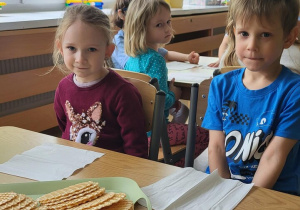 Dzieci siedzą przy stolikach, czekają na degustację miodu