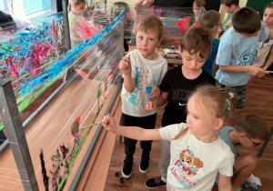 Dziewczynka i chłopcy malują farbami po folii