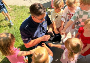 Pan policjant stempluje dzieciom ręce