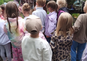 Dzieci słuchają pracownika kwiaciarni opowiadającego o roślinach