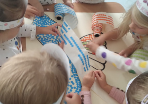 Dzieci wspólnie wykonują pracę plastyczną z kropek