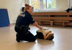 Policjantka pokazuje z chłopcem pozycję żółwia_Easy-Resize.com