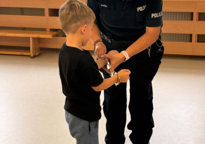 Policjantka zapina kajdanki na rękach chłopca