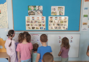 Dzieci znajdują się na tle tablic z planszami demonstracyjnymi o emocjach