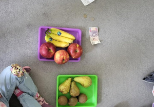 Na dywanie leżą owoce zakupione w sklepie reszta pieniędzy i paragon